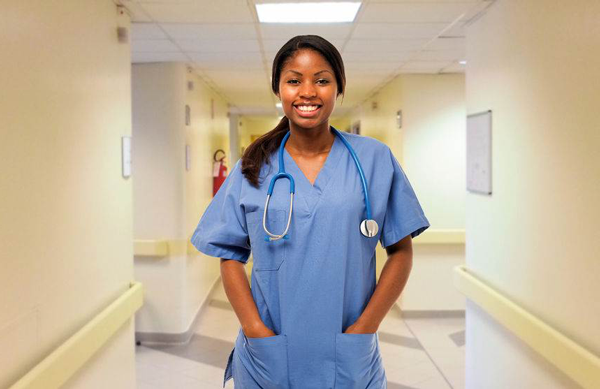 a nurse in blue scrubs with a stethoscope in a hospital hallway